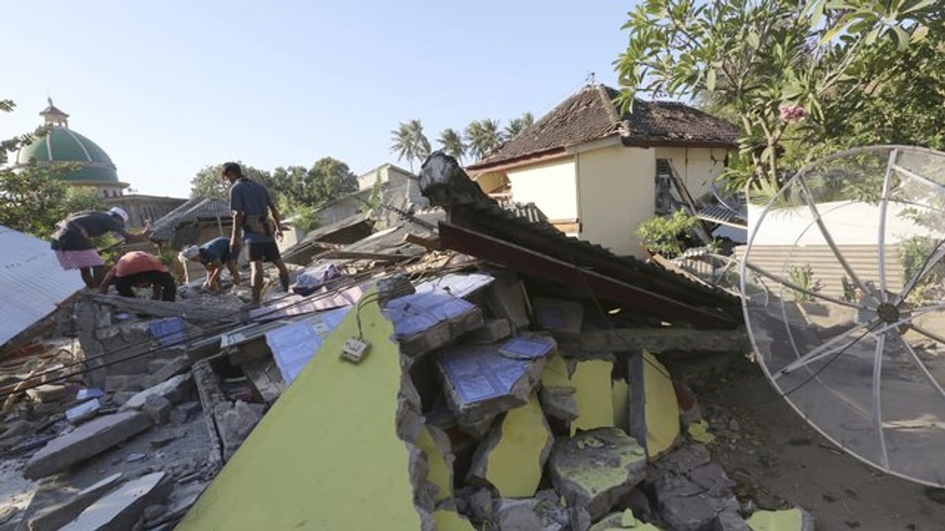 Dorfbewohner retten Gebrauchsgegenstände aus einem zerstörten Haus.