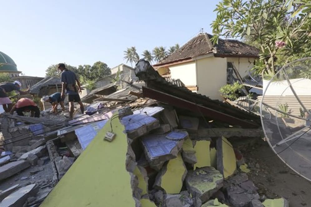 Dorfbewohner retten Gebrauchsgegenstände aus einem zerstörten Haus.