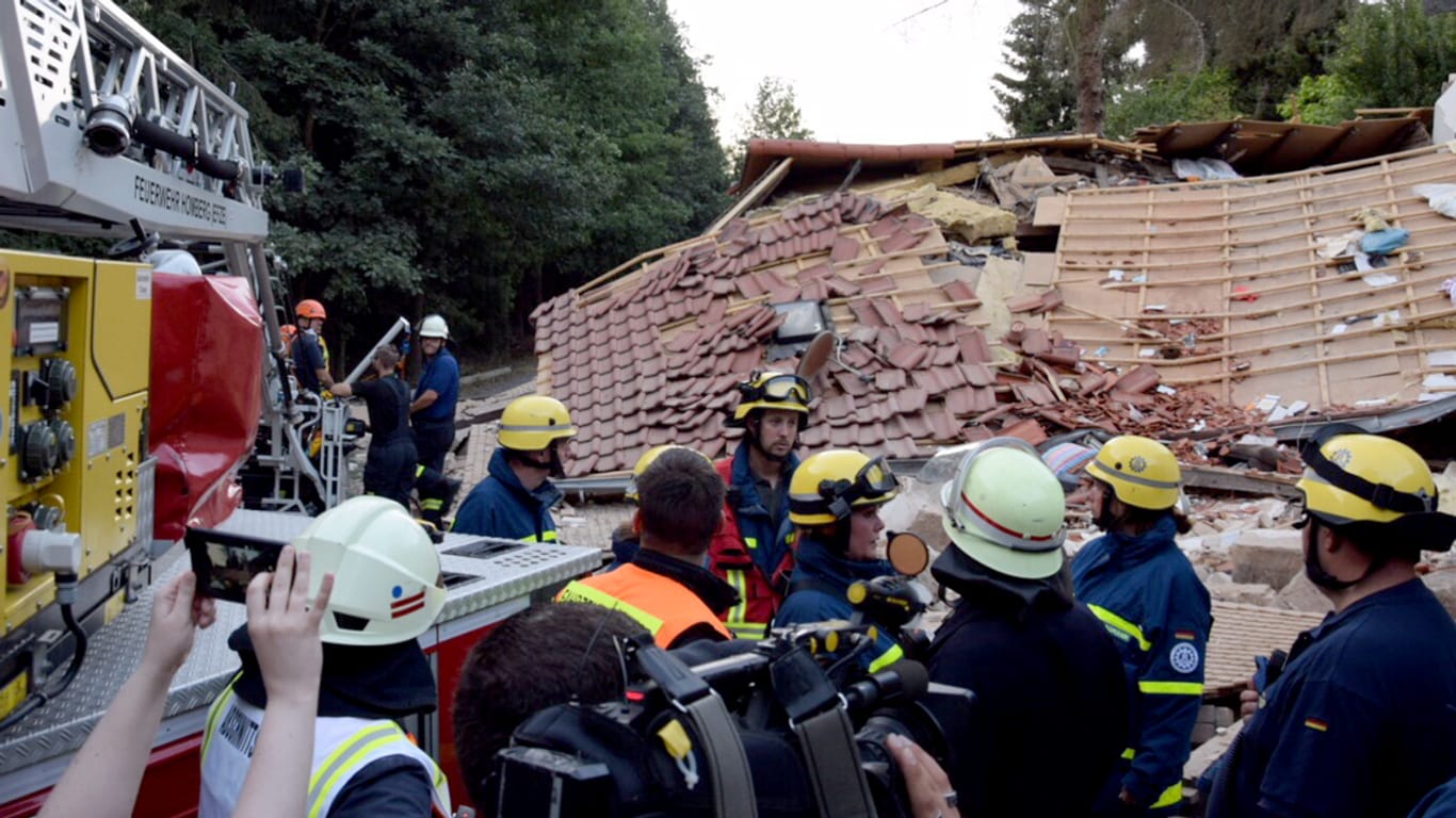 Feuerwehrleute stehen nach einer Gasexplosion vor Trümmerteilen eines eingestürzten Wohnhauses: Die Explosion ereignete sich am Montagnachmittag, die Feuerwehr war im Großeinsatz.