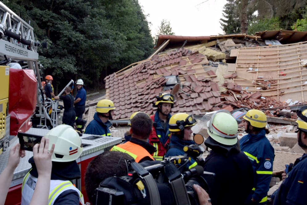 Feuerwehrleute stehen nach einer Gasexplosion vor Trümmerteilen eines eingestürzten Wohnhauses: Die Explosion ereignete sich am Montagnachmittag, die Feuerwehr war im Großeinsatz.