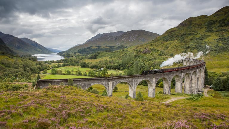 Viadukt mit Dampflok: Dieses Highlight in Schottland kennen Urlauber aus den Harry-Potter-Filmen. Darin fährt der Hogwarts-Express-Zug mit den Zauberschülern über diese Brücke.