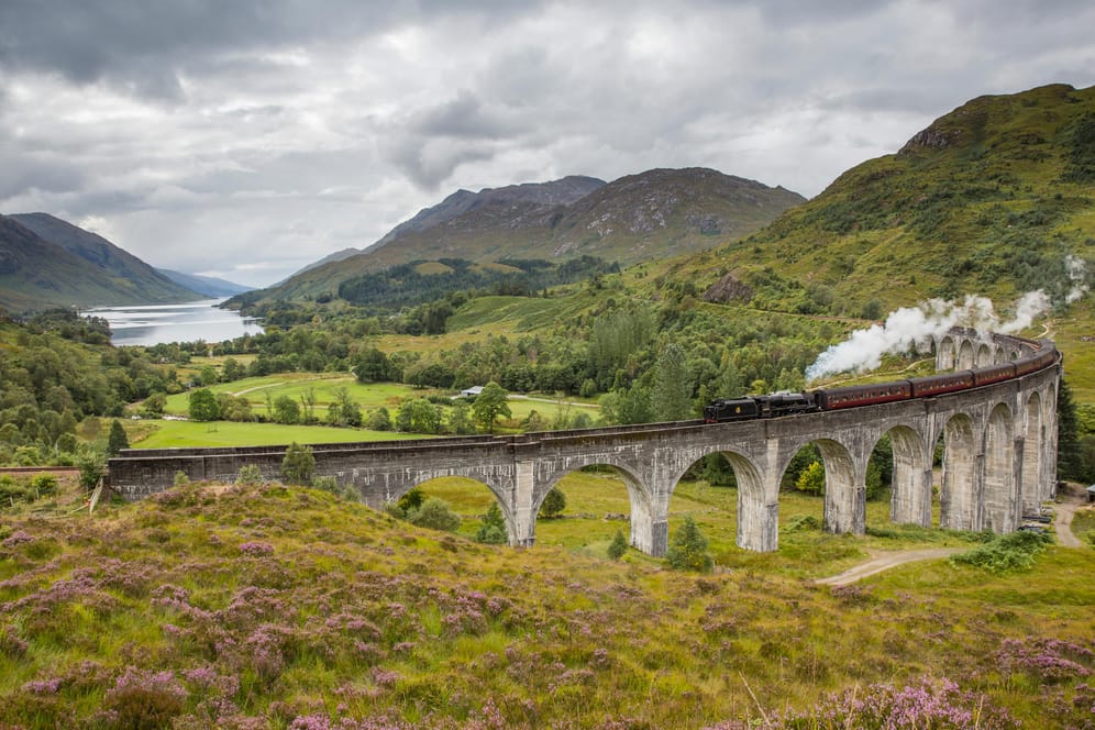 Viadukt mit Dampflok: Dieses Highlight in Schottland kennen Urlauber aus den Harry-Potter-Filmen. Darin fährt der Hogwarts-Express-Zug mit den Zauberschülern über diese Brücke.
