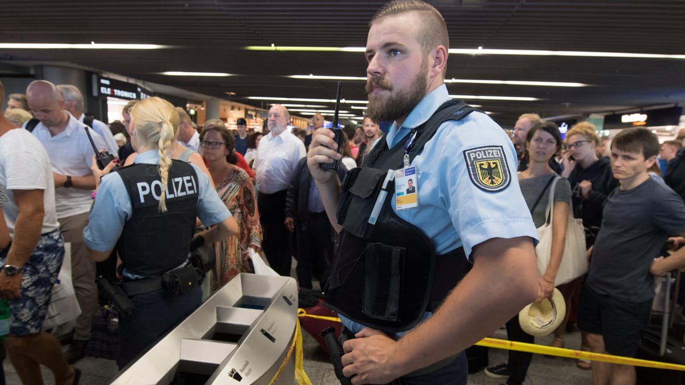 Polizisten und Passagiere stehen in Halle A im Terminal 1 des Flughafens Frankfurt: Grund für die Teilräumung ist ein Vorfall an der Sicherheitskontrolle, mindestens eine Person ist unberechtigt in den Sicherheitsbereich gelangt.