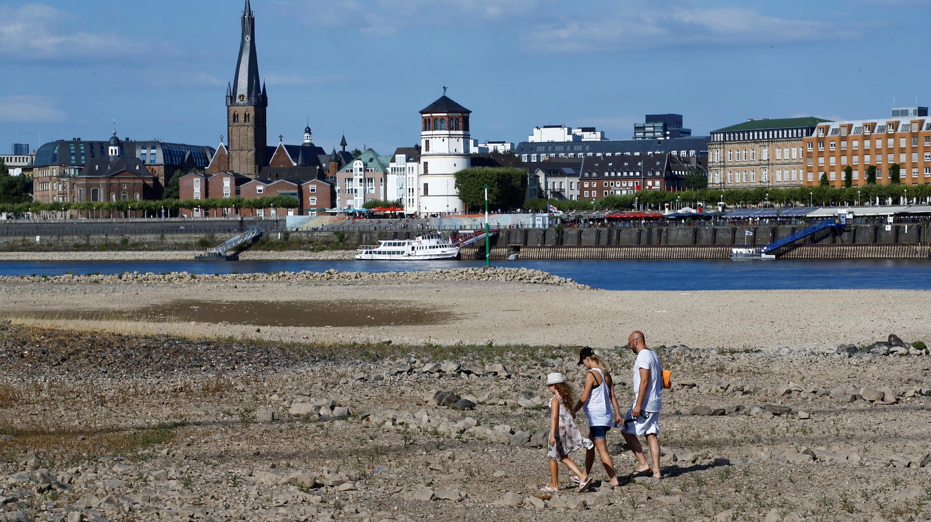 Dürresommer 2018 in Deutschland: Eine Familie läuft in Düsseldorf über ausgetrocknete Teile des Flussbetts des Rheins.