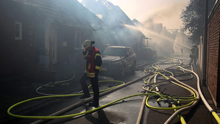 Ein Feuerwehrmann geht bei den Löscharbeiten in Siegburg an Häusern vorbei: Die Wohnhäuser waren durch einen Böschungsbrand direkt an der wichtigen Bahnstrecke Köln-Frankfurt in Brand geraten.