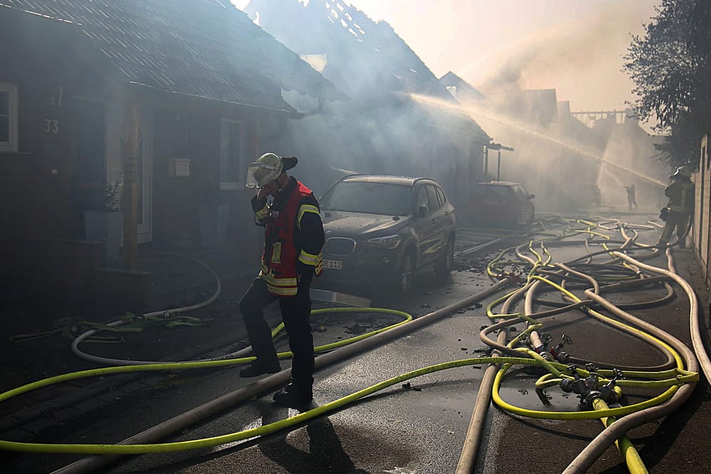 Ein Feuerwehrmann geht bei den Löscharbeiten in Siegburg an Häusern vorbei: Die Wohnhäuser waren durch einen Böschungsbrand direkt an der wichtigen Bahnstrecke Köln-Frankfurt in Brand geraten.
