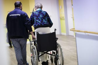 Ein Therapeut hilft einer älteren Frau: Seit Mitte der 90er Jahre gibt es neben den privaten Pflegeversicherungen die gesetzliche Pflegeversicherung.
