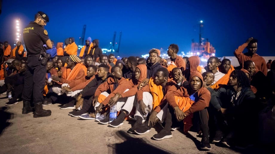 Flüchtlinge und ein Polizist im spanischen Hafen von Algeciras