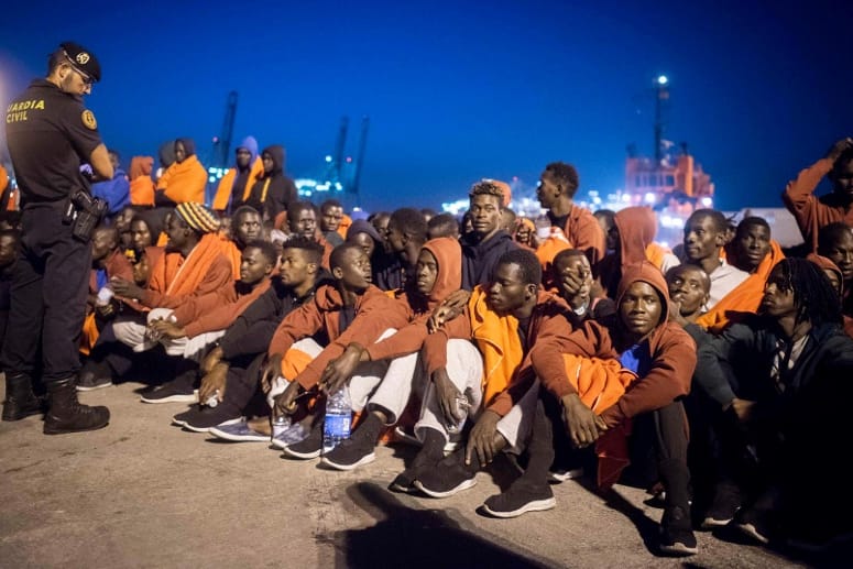 Flüchtlinge und ein Polizist im spanischen Hafen von Algeciras