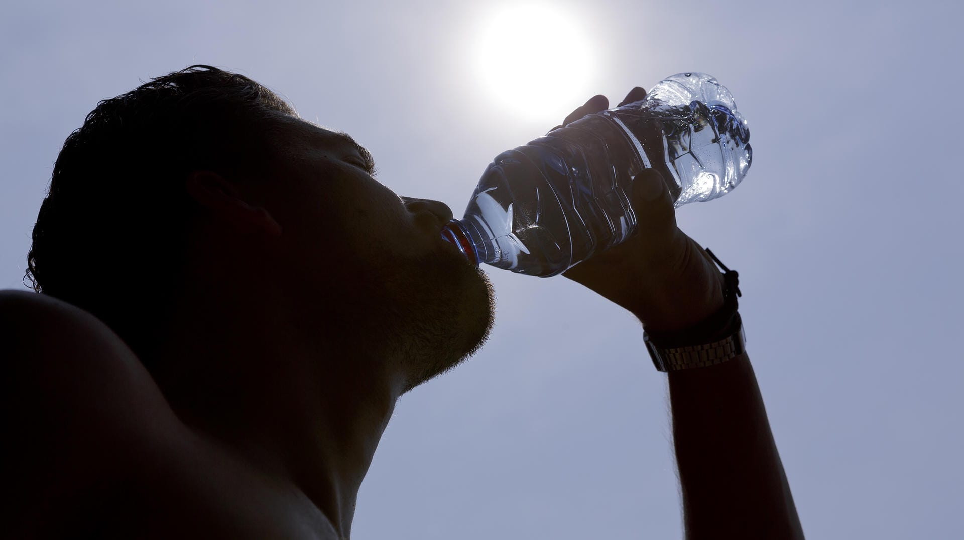 Mann mit Wasserflasche: Ob Wasser oder Fruchtschorle – viel zu trinken ist bei Hitze das A und O.