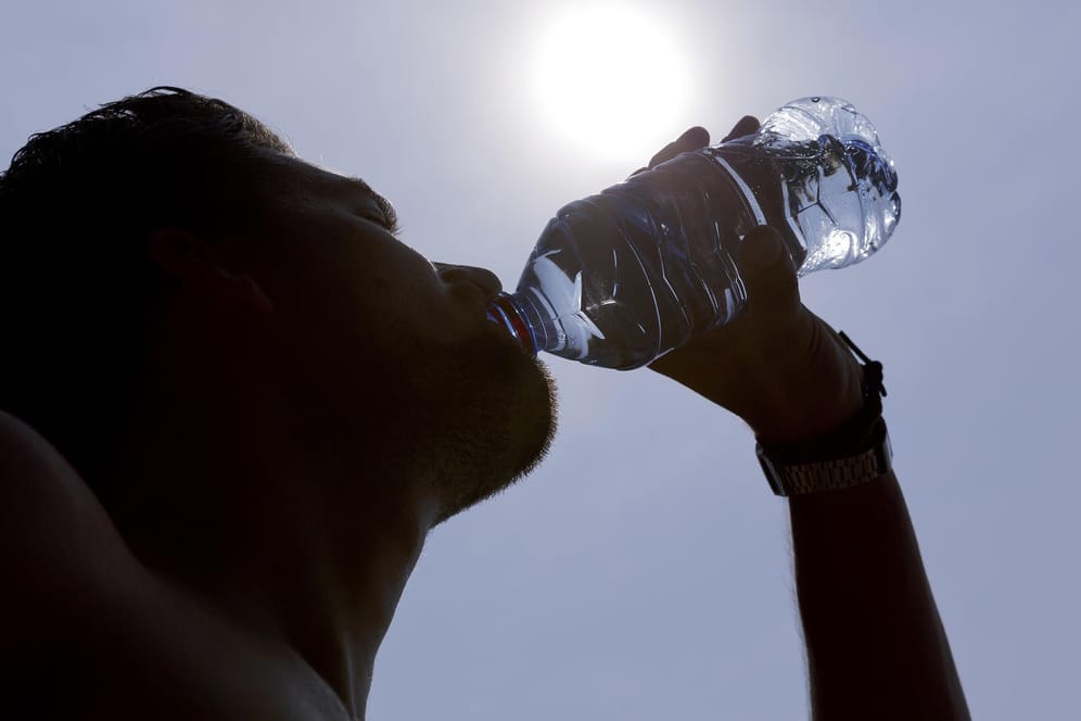 Mann mit Wasserflasche: Ob Wasser oder Fruchtschorle – viel zu trinken ist bei Hitze das A und O.