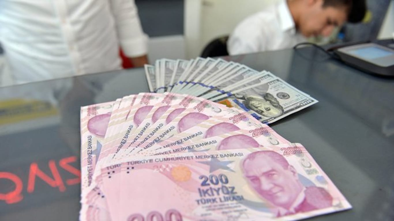 Ein Mitarbeiter einer Wechselstube in Ankara zeigt türkische Lira und US-Dollar.