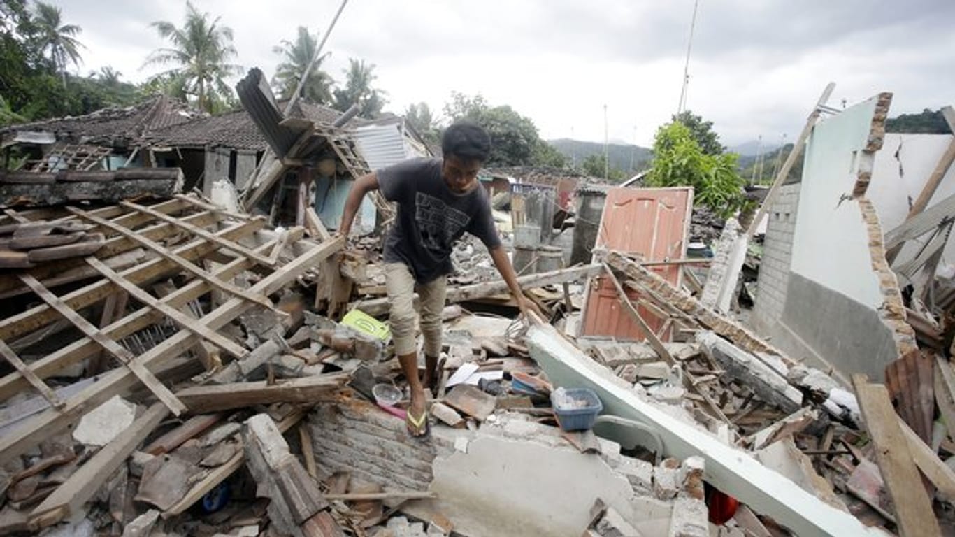 Ein Mann geht über die Trümmer eines vom Erdbeben zerstörten Hauses.