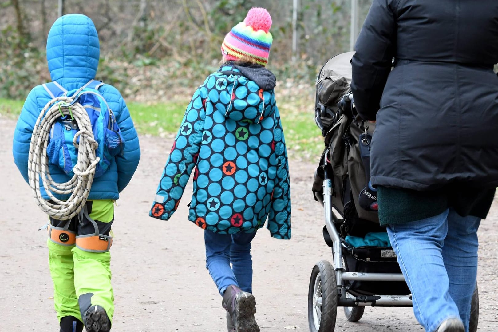 Frau mit Kindern und Kinderwagen unterwegs