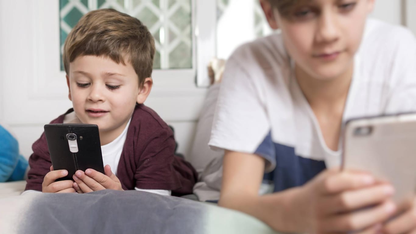 Zwei Kinder mit Smartphones: Wer in jungen Jahren zu viel aufs Handy schaut, hat ein höheres Risiko kurzsichtig zu werden.