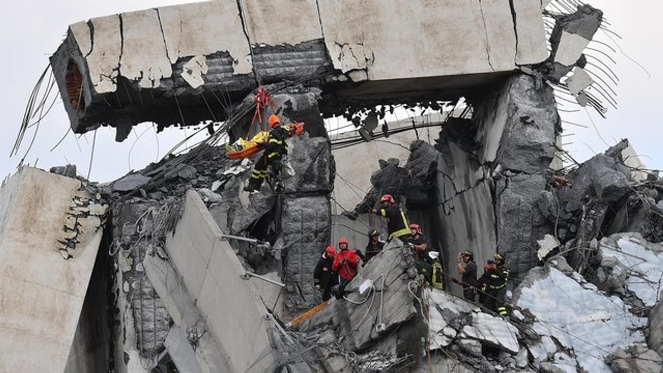 Feuerwehrleute bergen einen Verletzten aus den Trümmern der teilweise eingestürzten Autobahnbrücke Ponte Morandi.