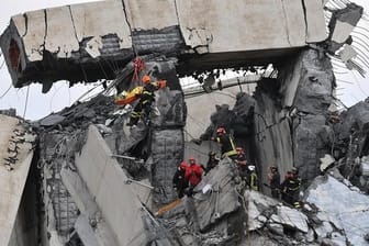 Feuerwehrleute bergen einen Verletzten aus den Trümmern der teilweise eingestürzten Autobahnbrücke Ponte Morandi.