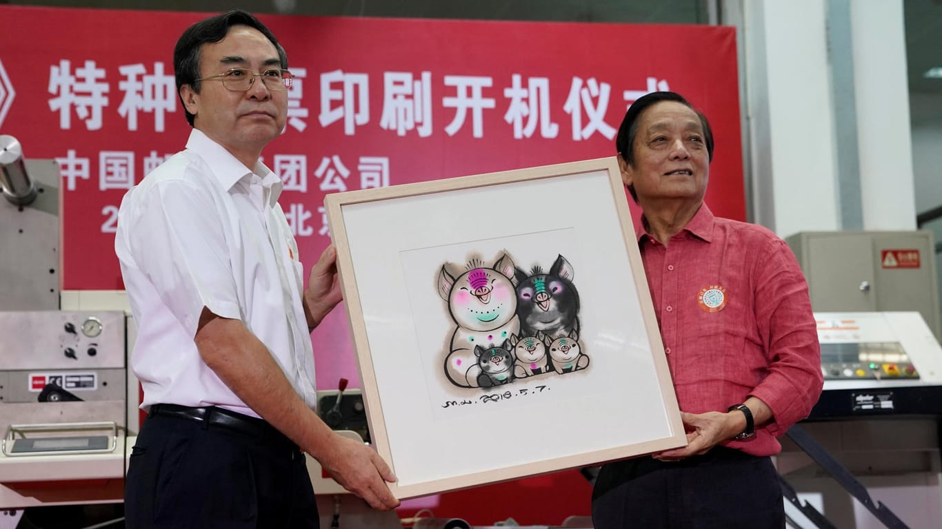Designer Han Meilin presents his design manuscript for a Year of the Pig stamp to Liu Aili, president of China Post, at a ceremony in Beijing