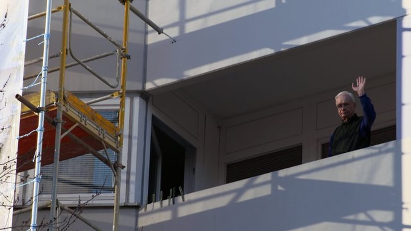 Ein älterer Mann winkt von einem eingerüsteten Balkon in einer Szene aus der ZDF-Reportage "Teurer Wohnen".