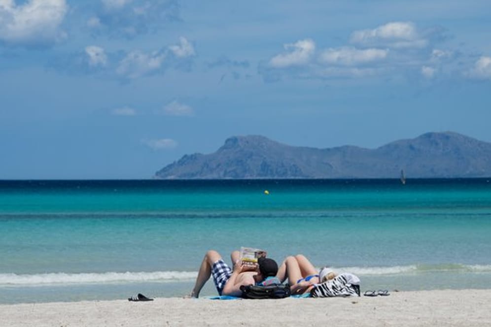 Urlauber liegen am Strand an der Platja de Muro im Norden der Mittelmeerinsel Mallorca.