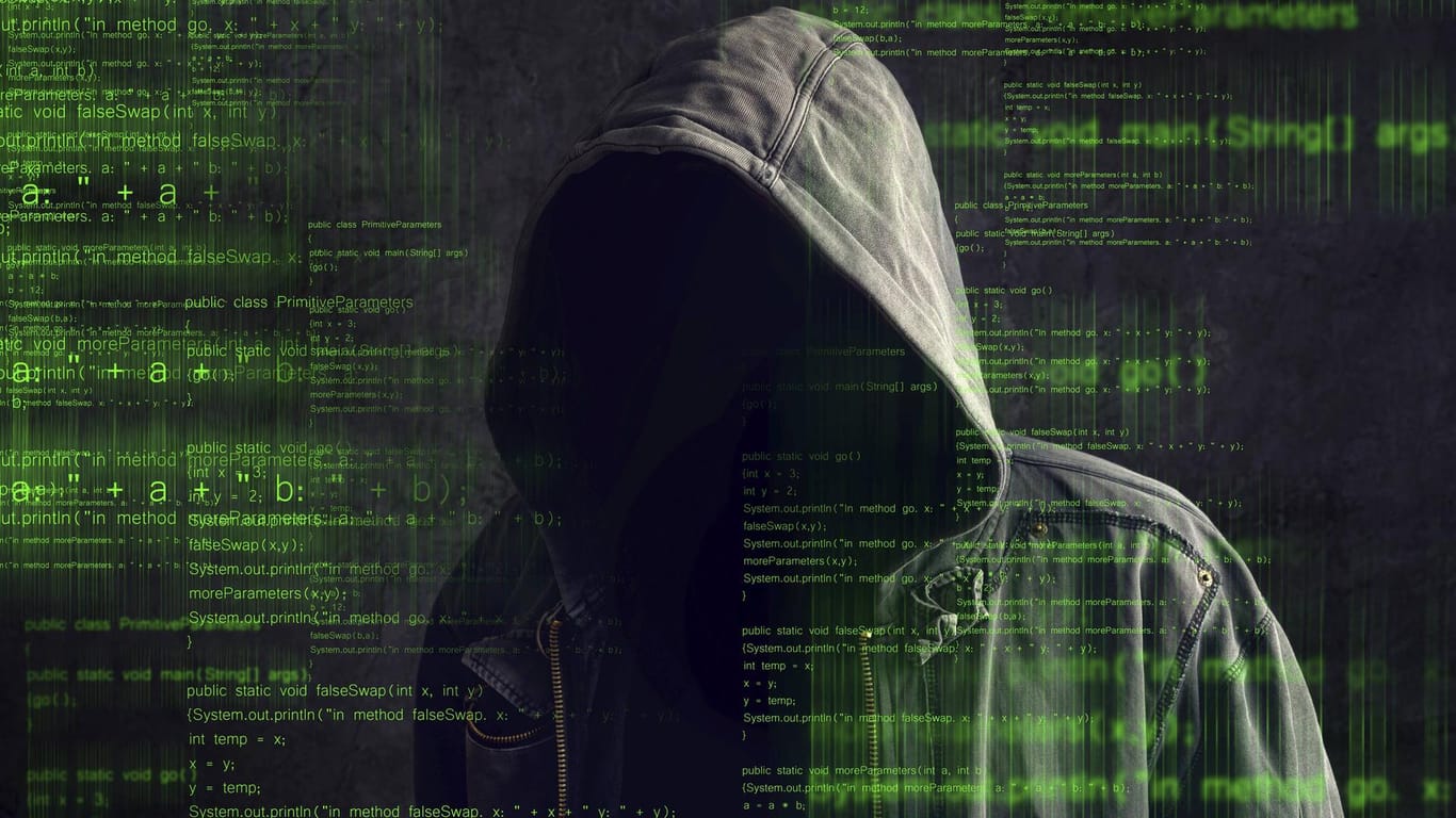 Mann mit Kapuze, der einen Hacker darstellen soll: Mit Kryptojacking kapern Unbekannte Fremdcomputer, um die Prozessorleistung zum Bitcoin-Schürfen zu nutzen.
