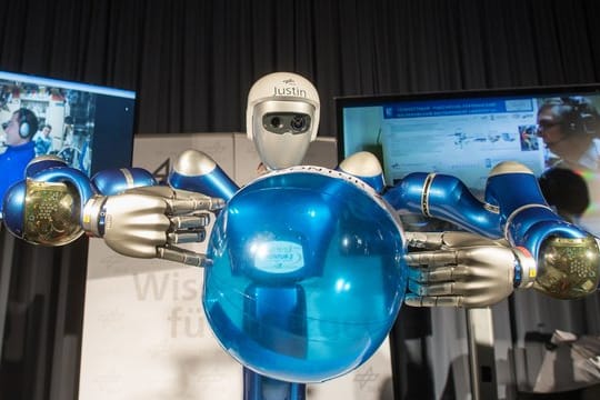 Der Roboter heißt Justin und balanciert einen blauen Ball.