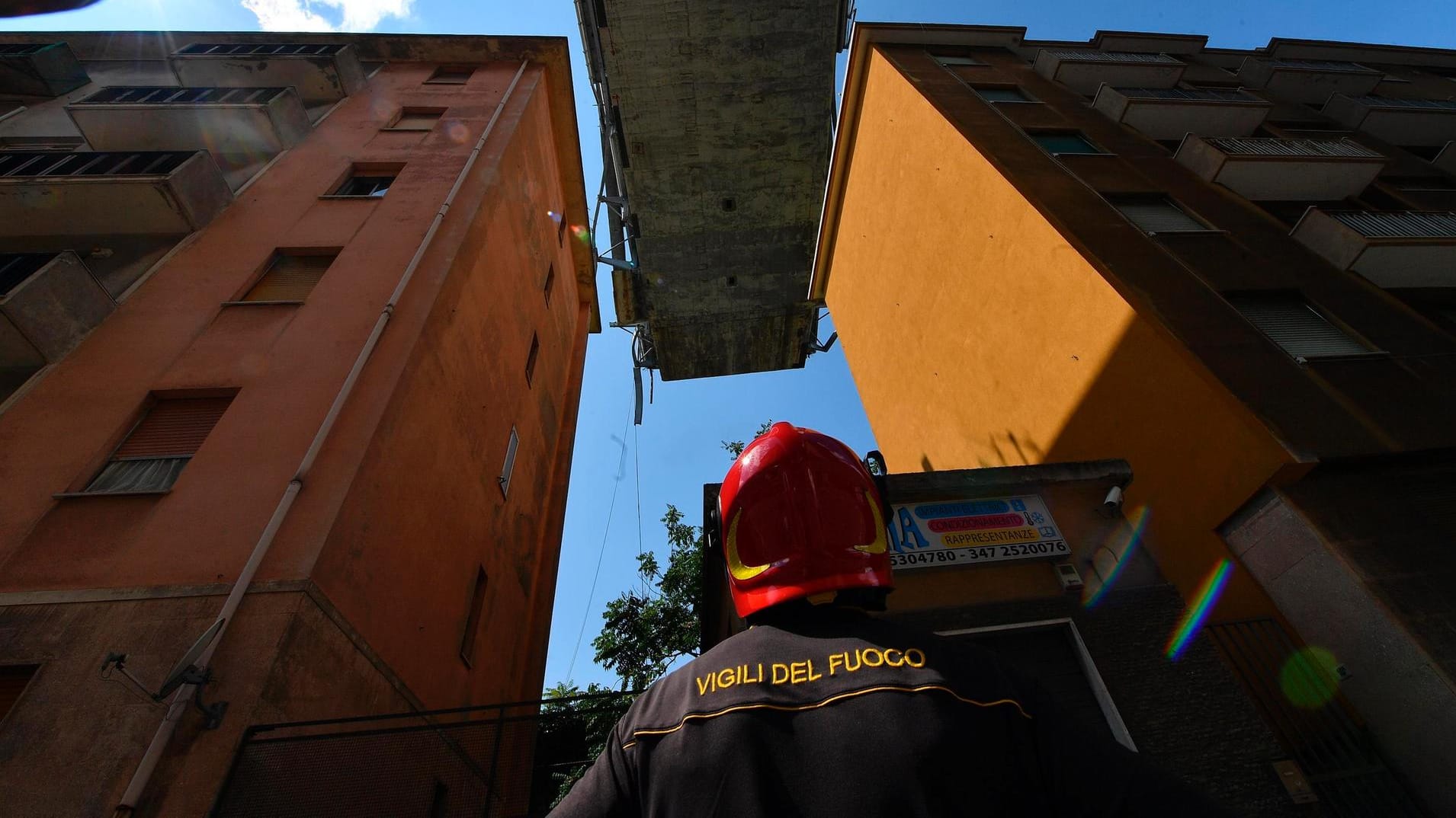 Genua: Ein Feuerwehrmann schaut auf die Reste der teilweise eingestürzte Morandi-Autobahnbrücke, die über evakuierte Wohnhäuser hinausragt.