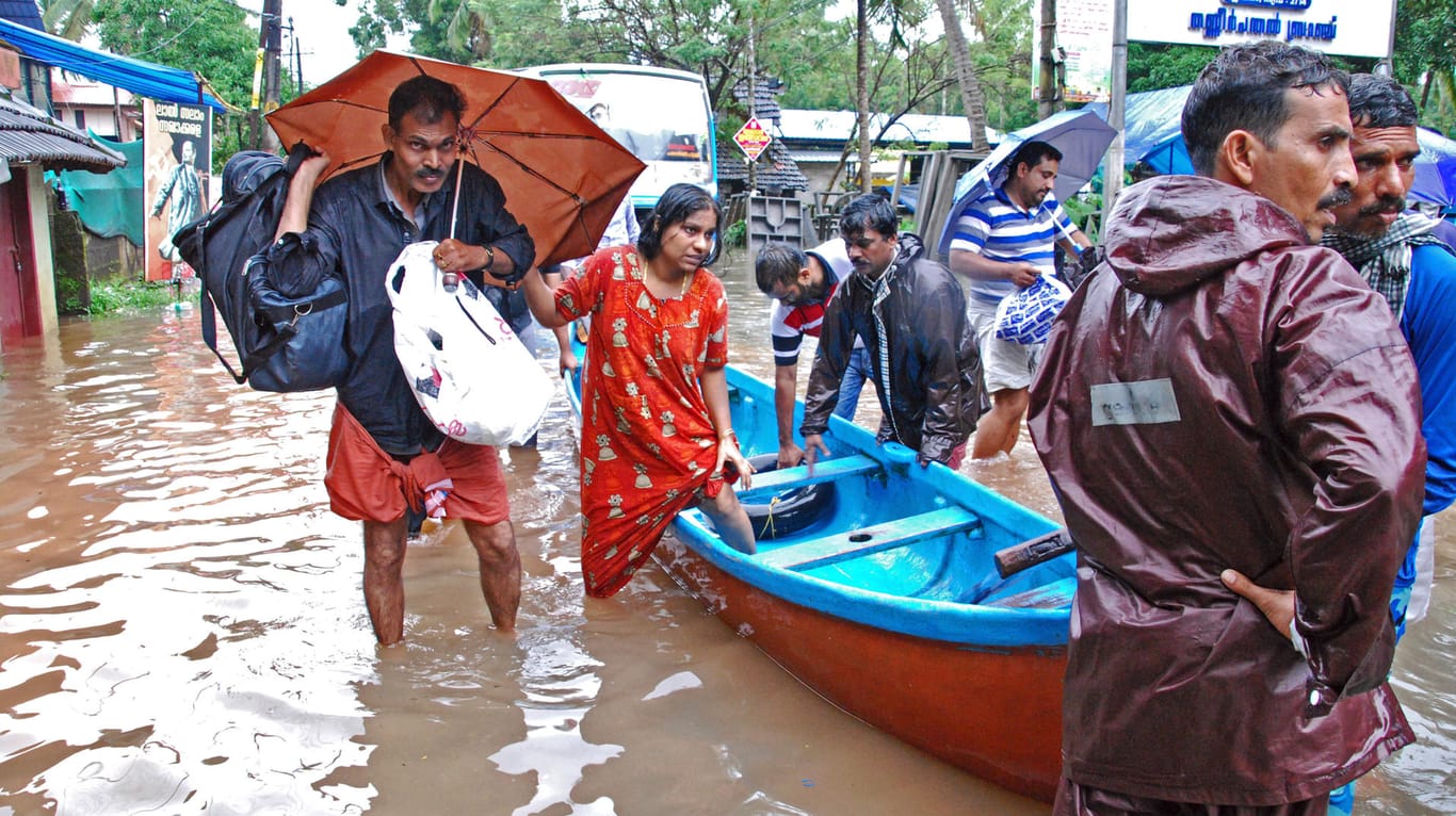 Flutopfer werden aus einem überschwemmten Gebiet evakuiert: Der indische Bundesstaat Kerala leidet unter dem schwersten Monsunregen seit Jahrzehnten.