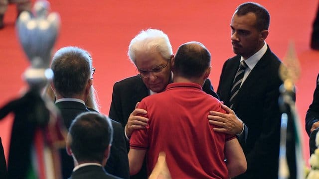 Italiens Präsident Mattarella umarmt bei der Trauerfeier am Samstag den Verwandten eines Opfers. Italiens Präsident Mattarella umarmt bei der Trauerfeier am Samstag den Verwandten eines Opfers.