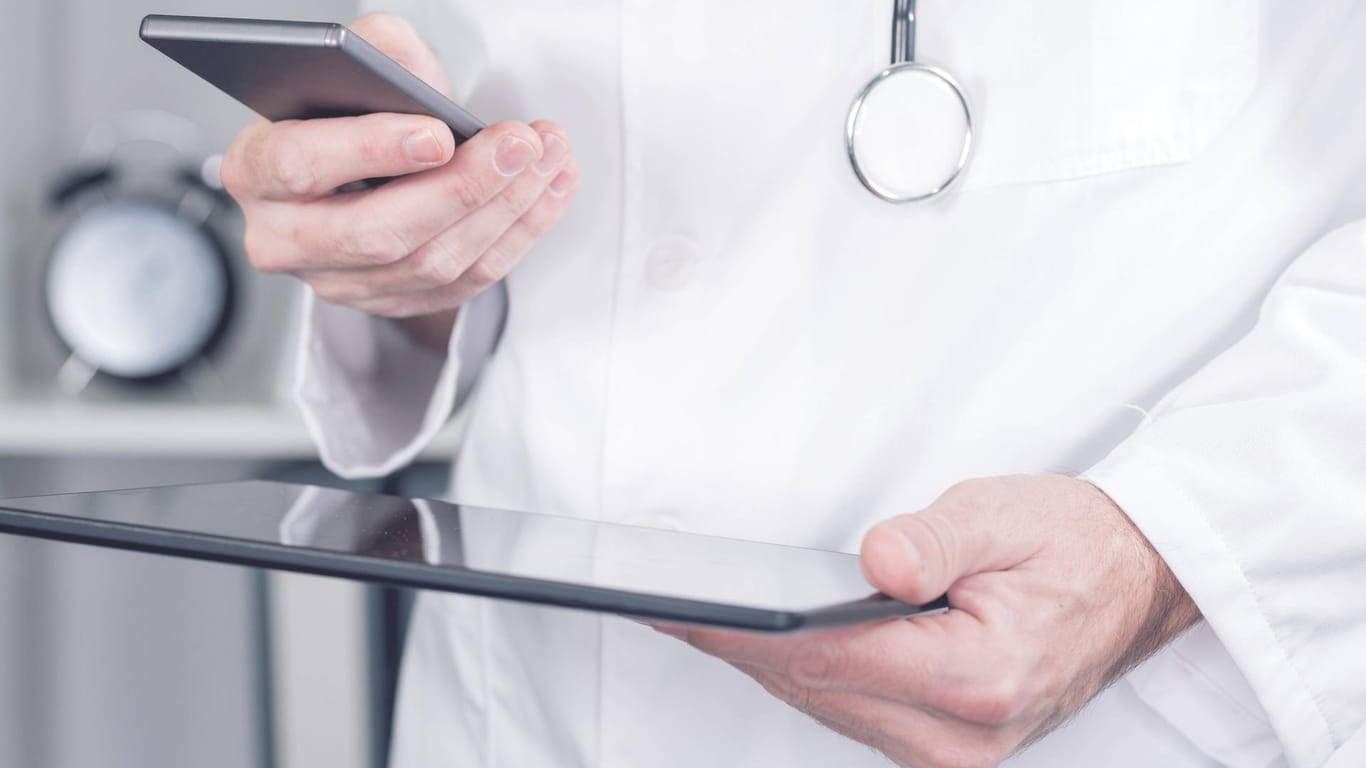Arzt beim Nutzen eines Smartphones und Tablet-PCs (Symbolbild): Ein Arzt soll von seinen Patientinnen Sex als Gegenleistung für das Verschreiben von Medikamenten verlangt haben.