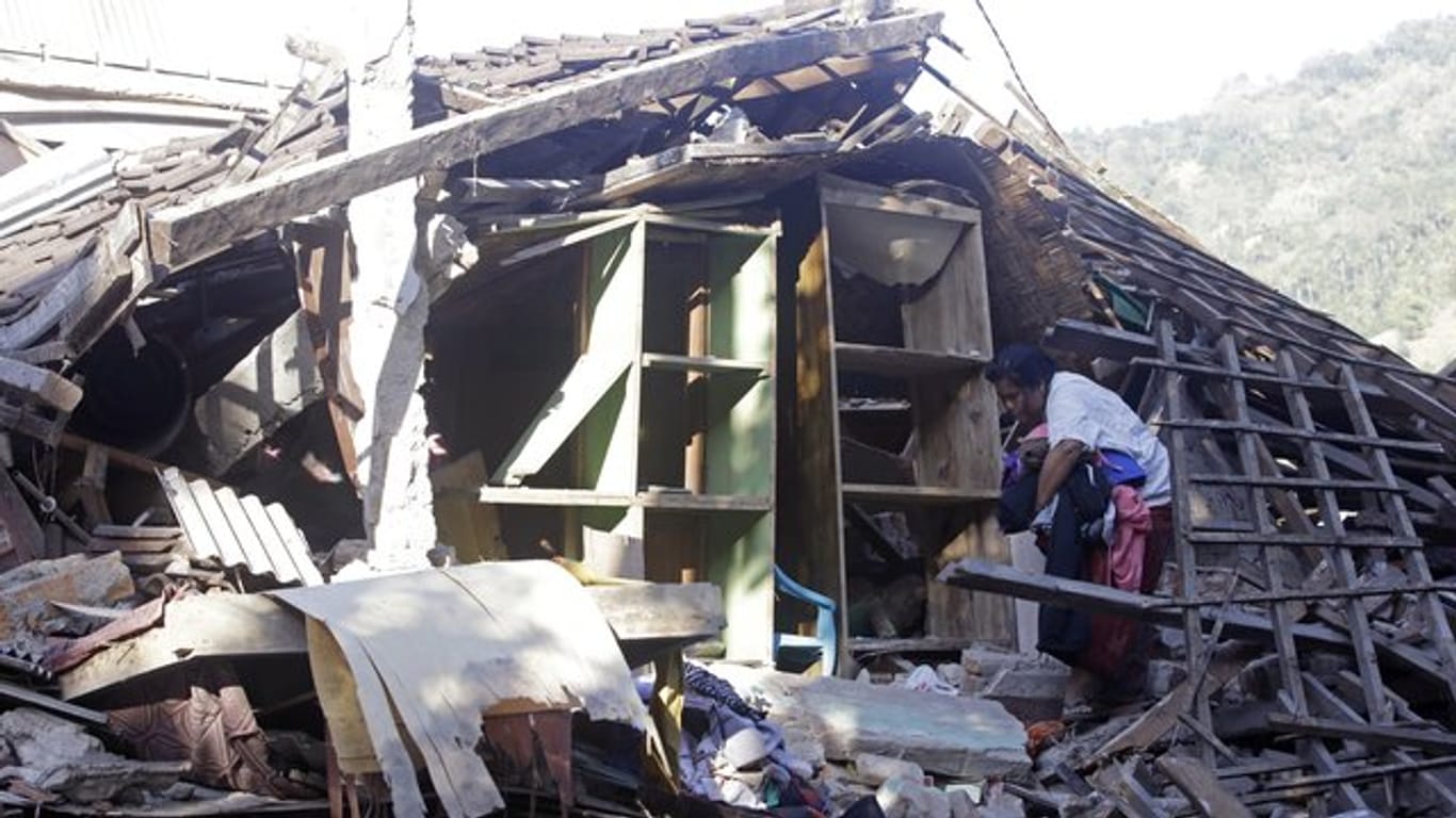 Lombok kommt nicht zur Ruhe: Eine Frau sammelt Habseligkeiten in der Ruine ihres durch ein Erdbeben zerstörten Hauses.