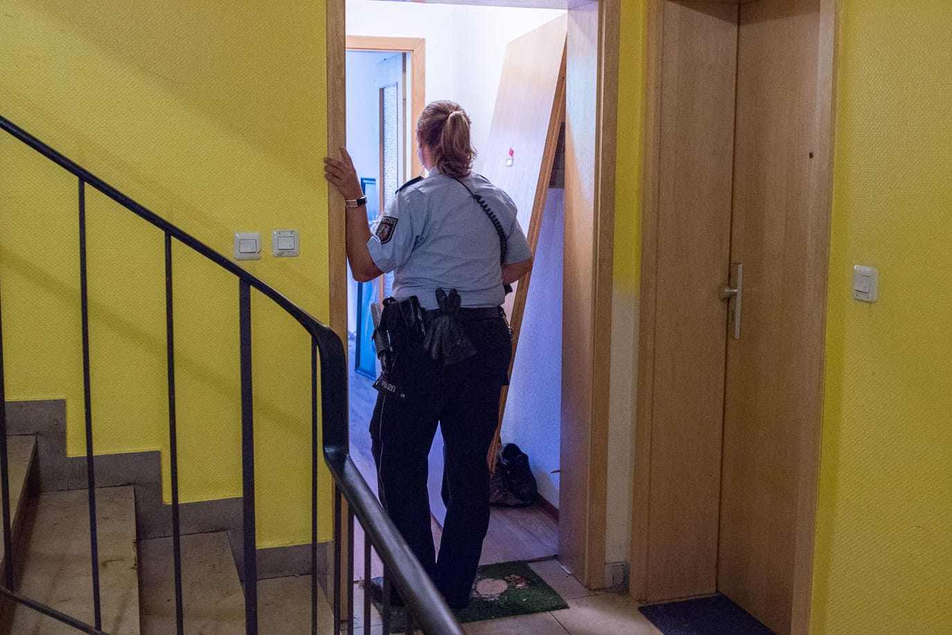 Düsseldorf: Eine Polizistin steht im Eingang einer Wohnung, die Spezialkräfte im Rahmen einer Fahndung durchsuchten. Ein Mann hatte auf der Straße eine Frau tödlich verletzt.