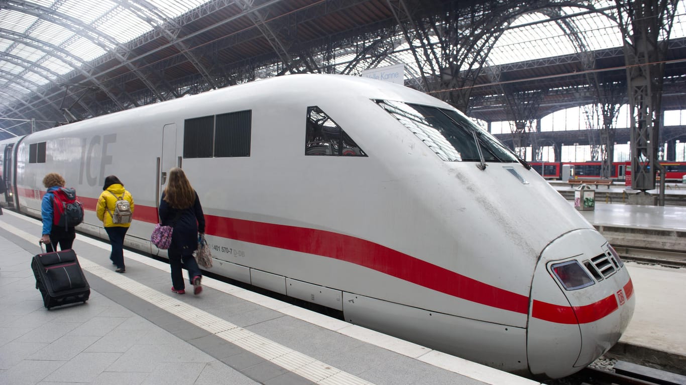 Reisende gehen im Hauptbahnhof in Leipzig an einen ICE vorbei.