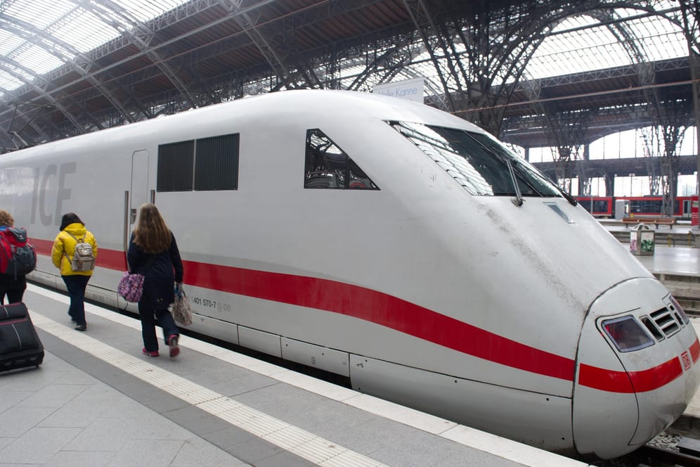 Reisende gehen im Hauptbahnhof in Leipzig an einen ICE vorbei.