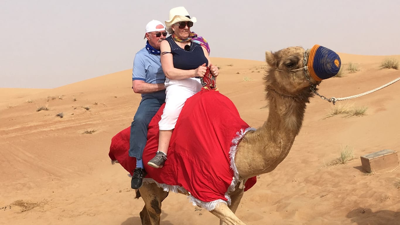 Erste Staffel von "Mit 80 Jahren um die Welt: Bernd und Christina beim Kamelreiten in der Wüste nahe Dubai.