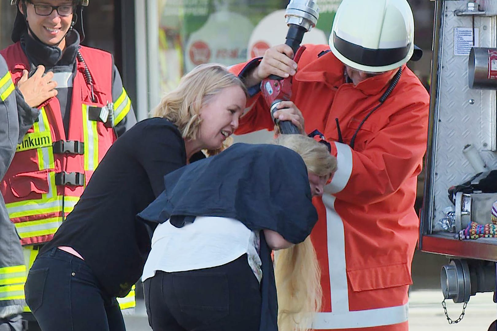 Ein Feuerwehrmann wäscht einer Friseurkundin die Haare aus: Die Feuerwehr eilte bei einem Brand in einem Supermarkt auch einer Friseurkundin zu Hilfe.