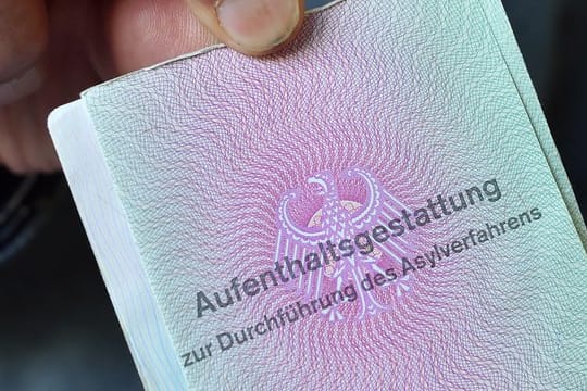 Ein Mann aus Syrien zeigt in einer Gemeinschaftsunterkunft für Flüchtlinge seine "Aufenthaltsgestattung".