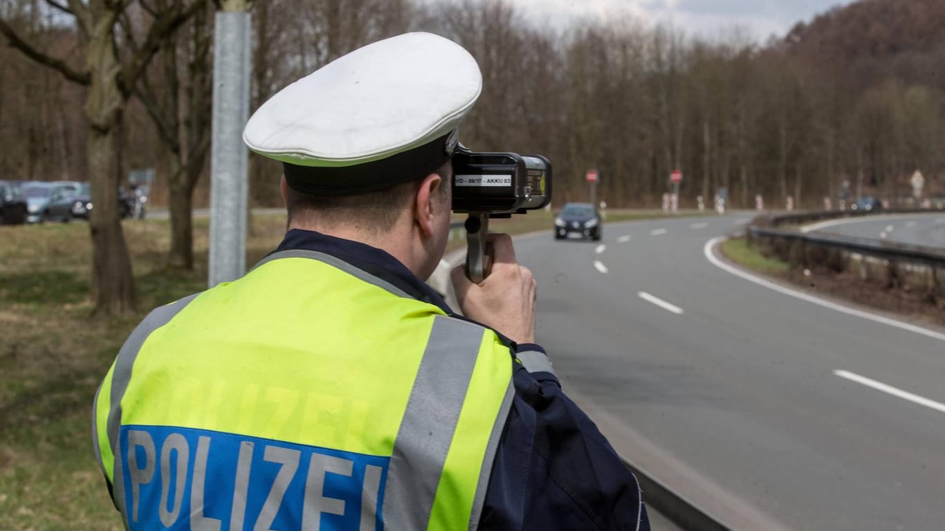 Polizeibeamter in Uniform bei der Geschwindigkeitsmessung bei einem PKW mit einem Lasermessgerät (Symbolbild): In der Stadt Hagen wurde ein Raser mit mehr als 100 km/h über der Geschwindigkeitsbegrenzung erwischt. Besonders schockierend: Im Wagen saßen zwei Kinder auf dem Rücksitz.