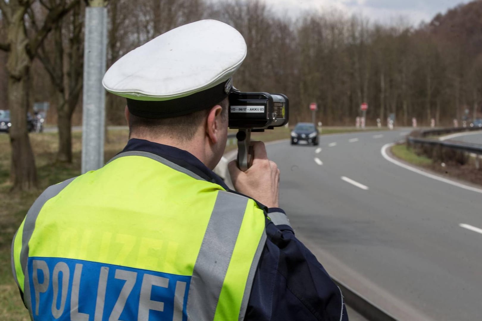 Polizeibeamter in Uniform bei der Geschwindigkeitsmessung bei einem PKW mit einem Lasermessgerät (Symbolbild): In der Stadt Hagen wurde ein Raser mit mehr als 100 km/h über der Geschwindigkeitsbegrenzung erwischt. Besonders schockierend: Im Wagen saßen zwei Kinder auf dem Rücksitz.
