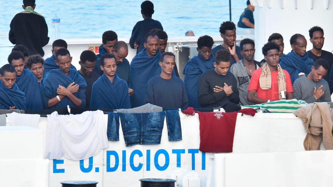 Migranten beten an Bord des italienischen Küstenwachschiffes "Diciotti": Sollte es keine Lösung über die Aufnahme der Migranten geben, droht Italien, seine EU-Zahlungen einzustellen.