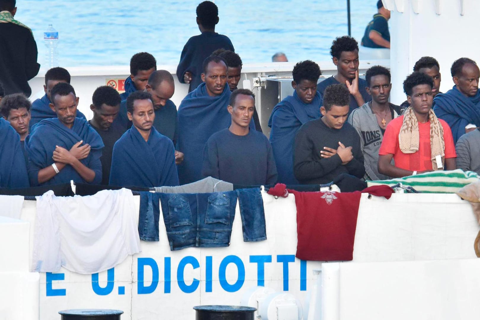 Migranten beten an Bord des italienischen Küstenwachschiffes "Diciotti": Sollte es keine Lösung über die Aufnahme der Migranten geben, droht Italien, seine EU-Zahlungen einzustellen.