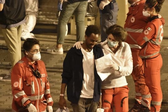 Ein Migrant spricht mit einer Helferin des Roten Kreuzes als er Bord der "Diciotti" geht.