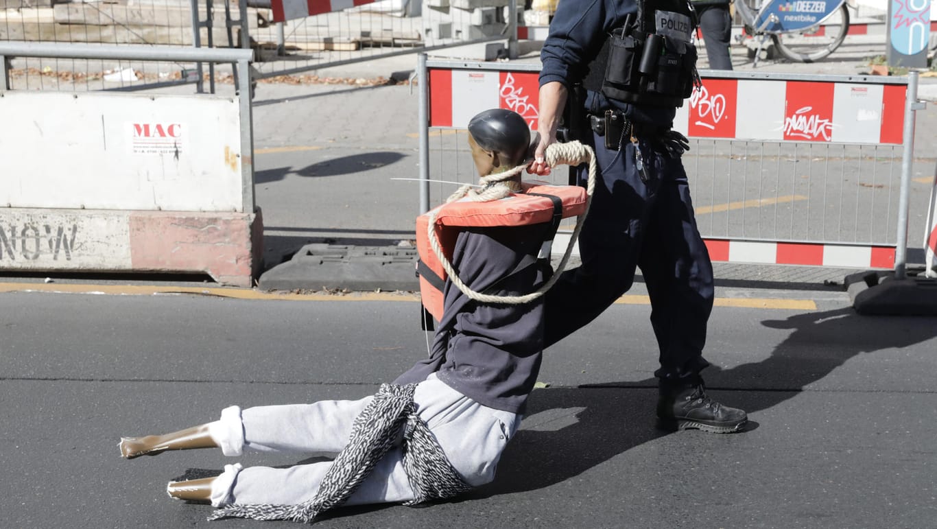 Ungewöhnlicher Einsatz in Berlin Ein Polizist trägt eine als Flüchtling verkleidete Schaufensterpuppe, die zuvor an einem Baukran am Hermannplatz hing.