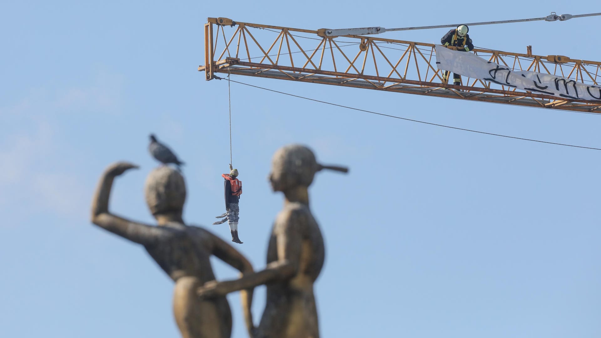 Die Schaufensterpuppe, verkleidet als Flüchtling, hängt an einem Baukran am Hermannplatz.