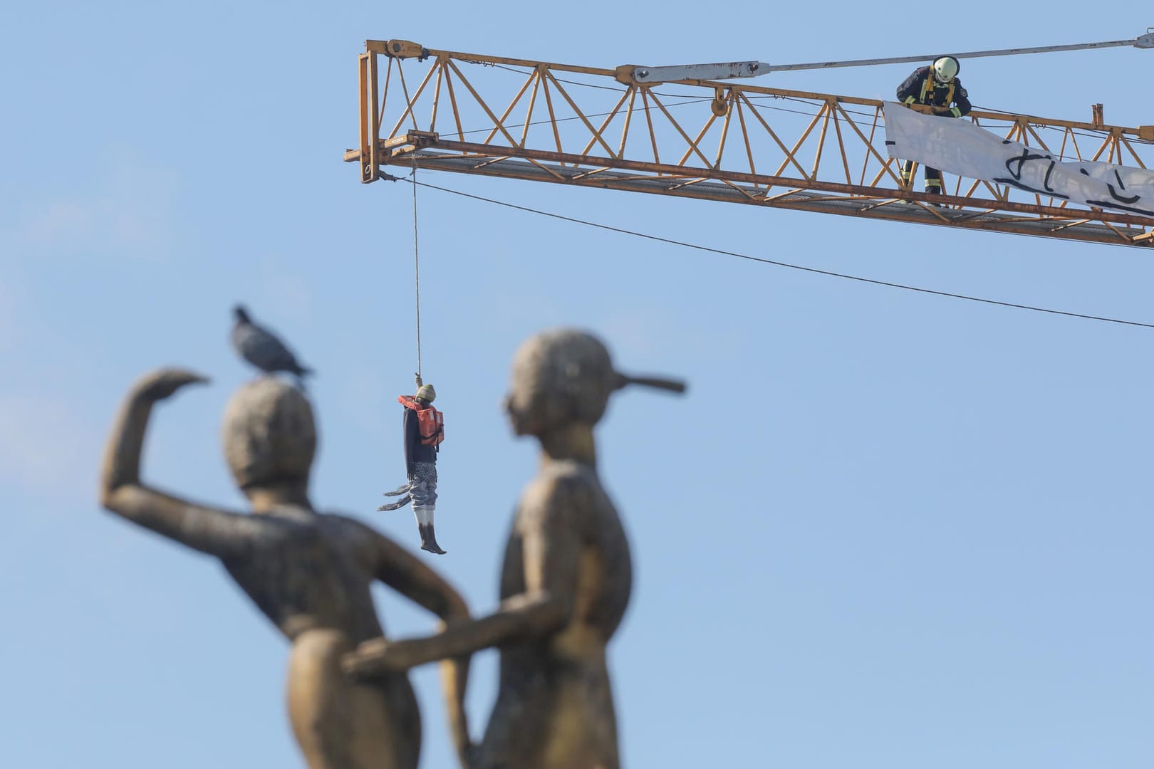 Die Schaufensterpuppe, verkleidet als Flüchtling, hängt an einem Baukran am Hermannplatz.