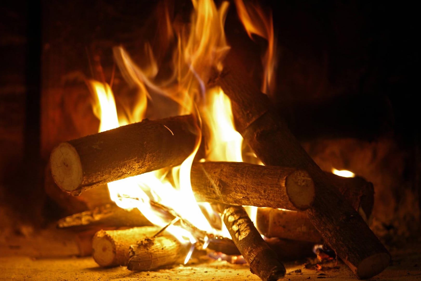 Holz brennt in einem Kamin: Feuchtes Holz eignet sich nicht für den Kamin und die Verbrennung ist laut Gesetz verboten.