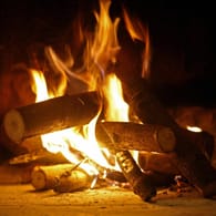 Holz brennt in einem Kamin: Feuchtes Holz eignet sich nicht für den Kamin und die Verbrennung ist laut Gesetz verboten.