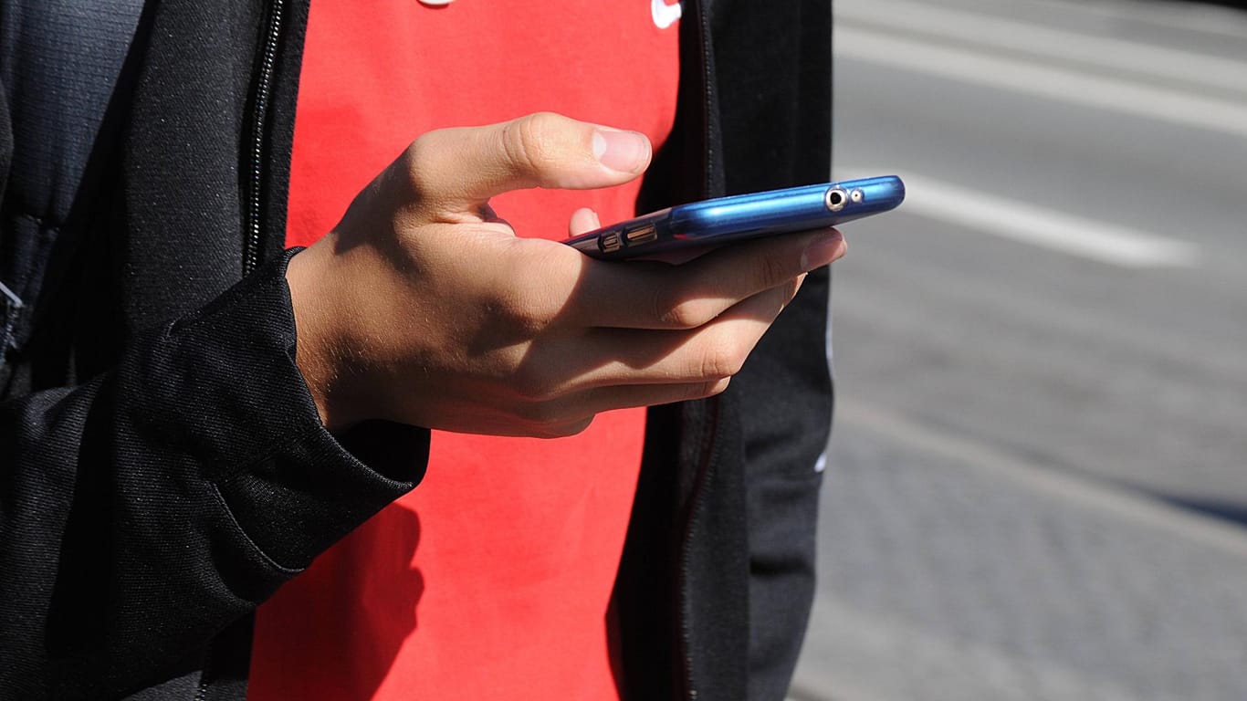 Eine Hand hält ein Smartphone: Mit der Öffi-App können Nutzer beispielsweise nachschauen, wann der nächste Bus in ihrer Nähe fährt. (Symbolbild)