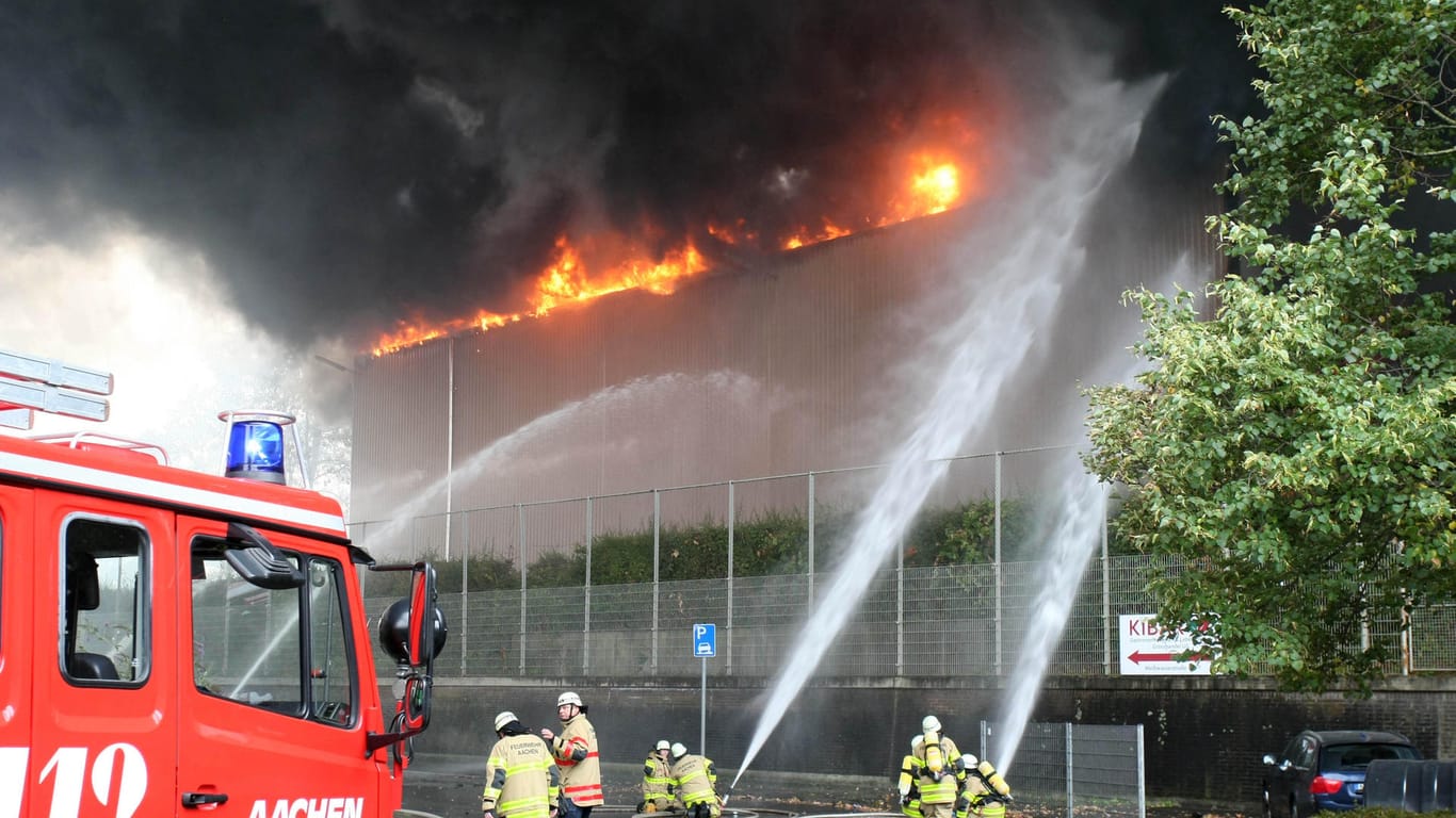 Feuerwehrleute löschen eine Gewerbehalle, in der Elektroschrott in Brand geraten ist: Die Halle brannte in vollem Ausmaß.