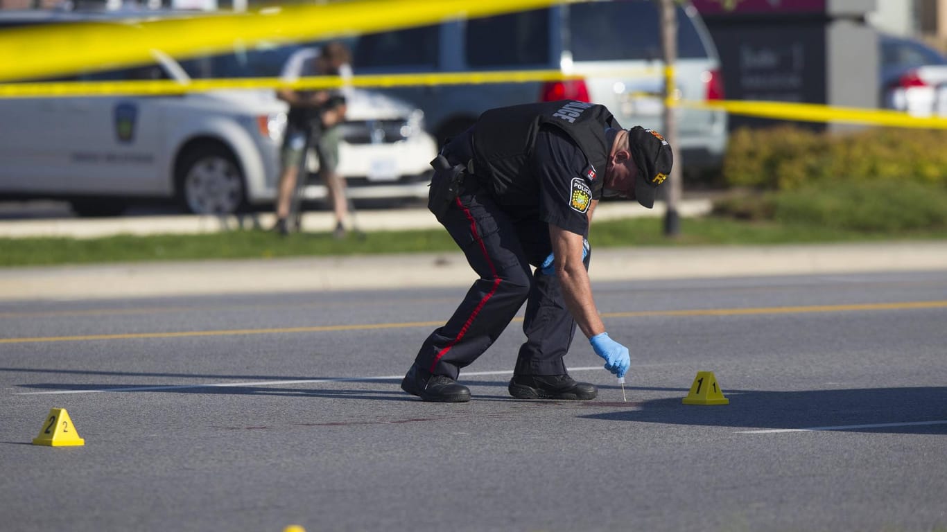Kanadischer Polizeibeamter sichert Spuren auf einer Straße nach einer Schießerei.